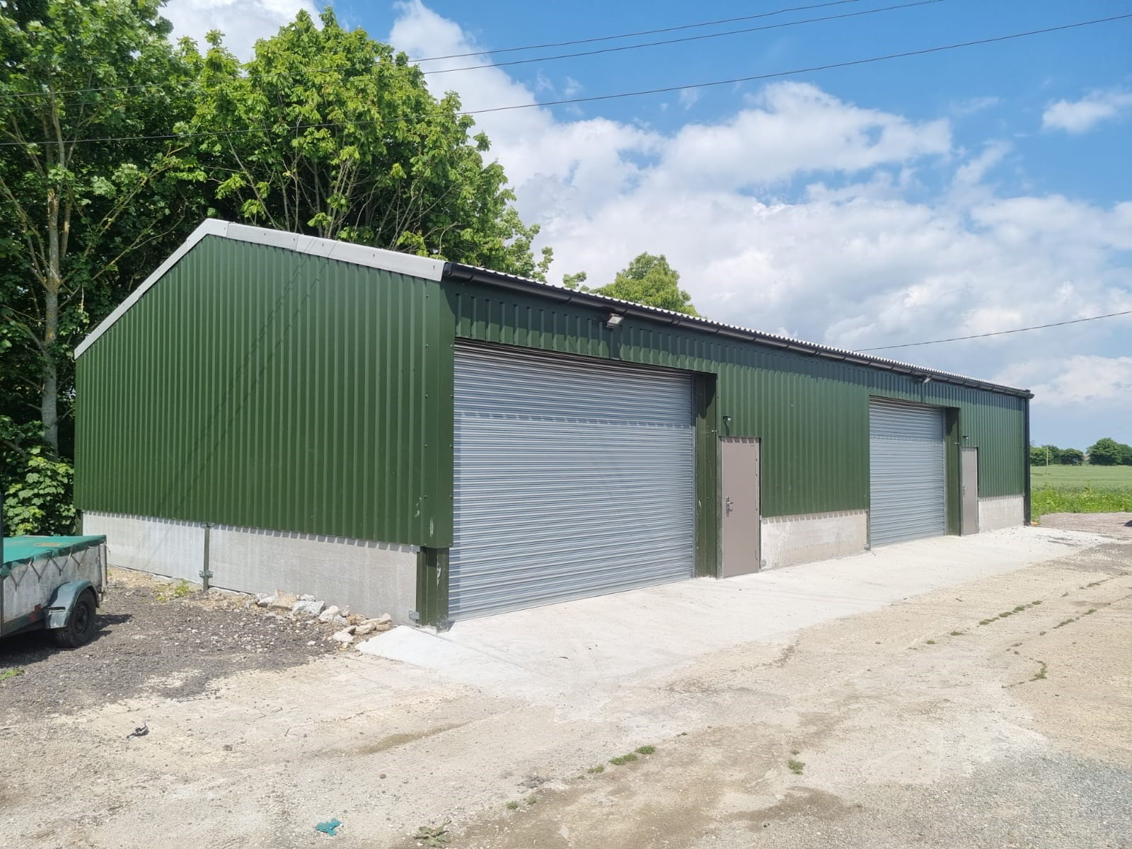 A steel frame building with green cladding. Featuring two roller shut doors and two personnel doors to the front.