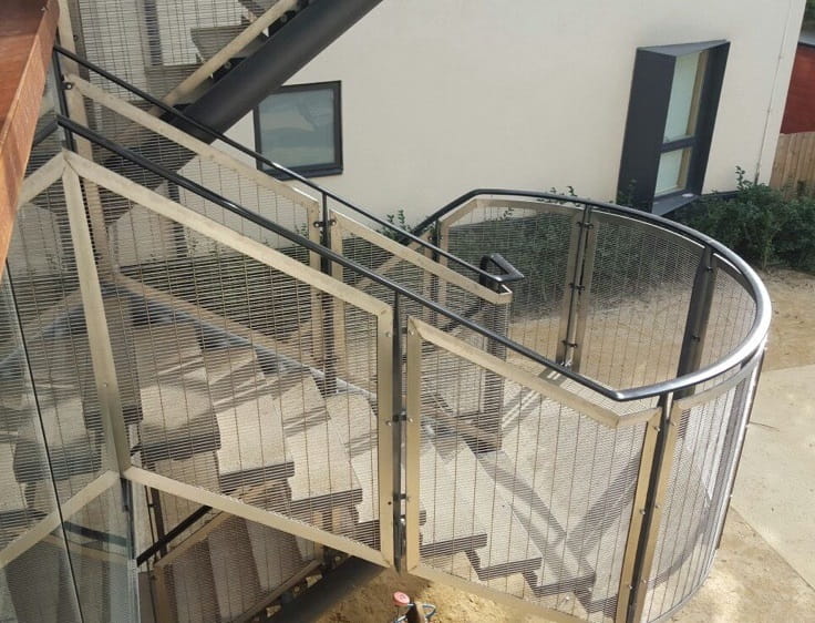 Curved external staircase with mesh filled decorative railings